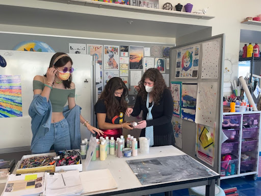 Juniors Maya Lewis, Kiki Dauphin and Isabella Rovetti gather materials in their IB Visual Arts class on Friday while dressed up in their Halloween costumes. Students were not allowed to wear violent or offensive costumes or any sort of facial obstruction or mask that was not a COVID-19 facial covering. 
