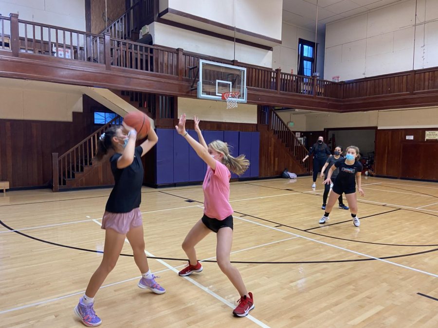 Freshman Ava Engle protects the ball from junior Roxanne Comerford today at basketball tryouts. Tryouts began Monday and will be held until Friday.