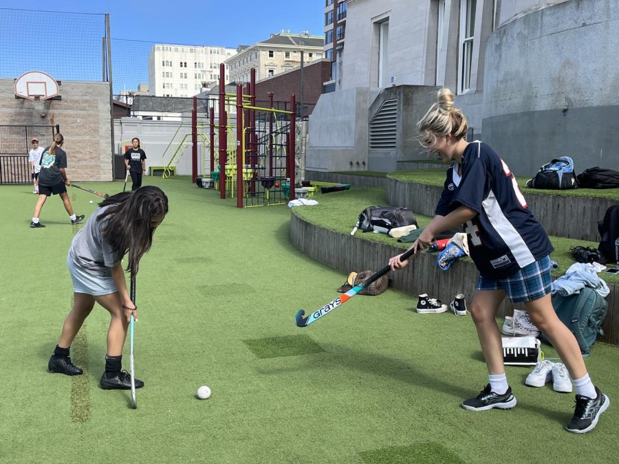 Juniors Sasha Miller and Zara Kirk pass the ball during warm up at field hockey’s Fun Friday practice. The team coined the name “Fun Friday” two years ago, and they compete in a series of games and scrimmages throughout practice.
