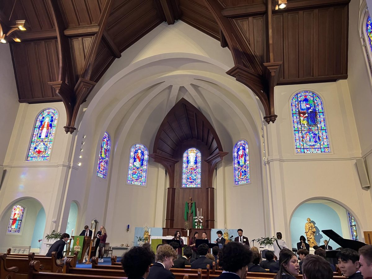 Students gather for All Saints’ Day mass at St. Vincent de Paul.The church features stained glass windows, which depict religious imagery, as well as architectural features from the Gothic European time periods.