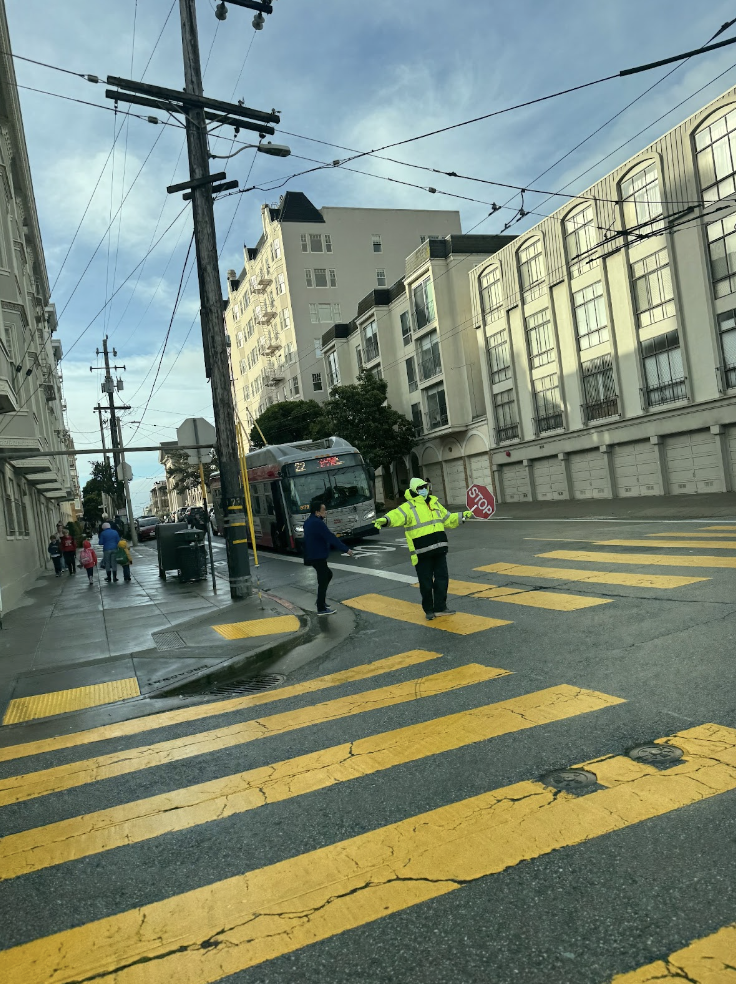 Students cross the street outside of the Broadway campus. Crossing guards are present outside school during drop-off and pick up times to ensure a smooth flow of traffic. 