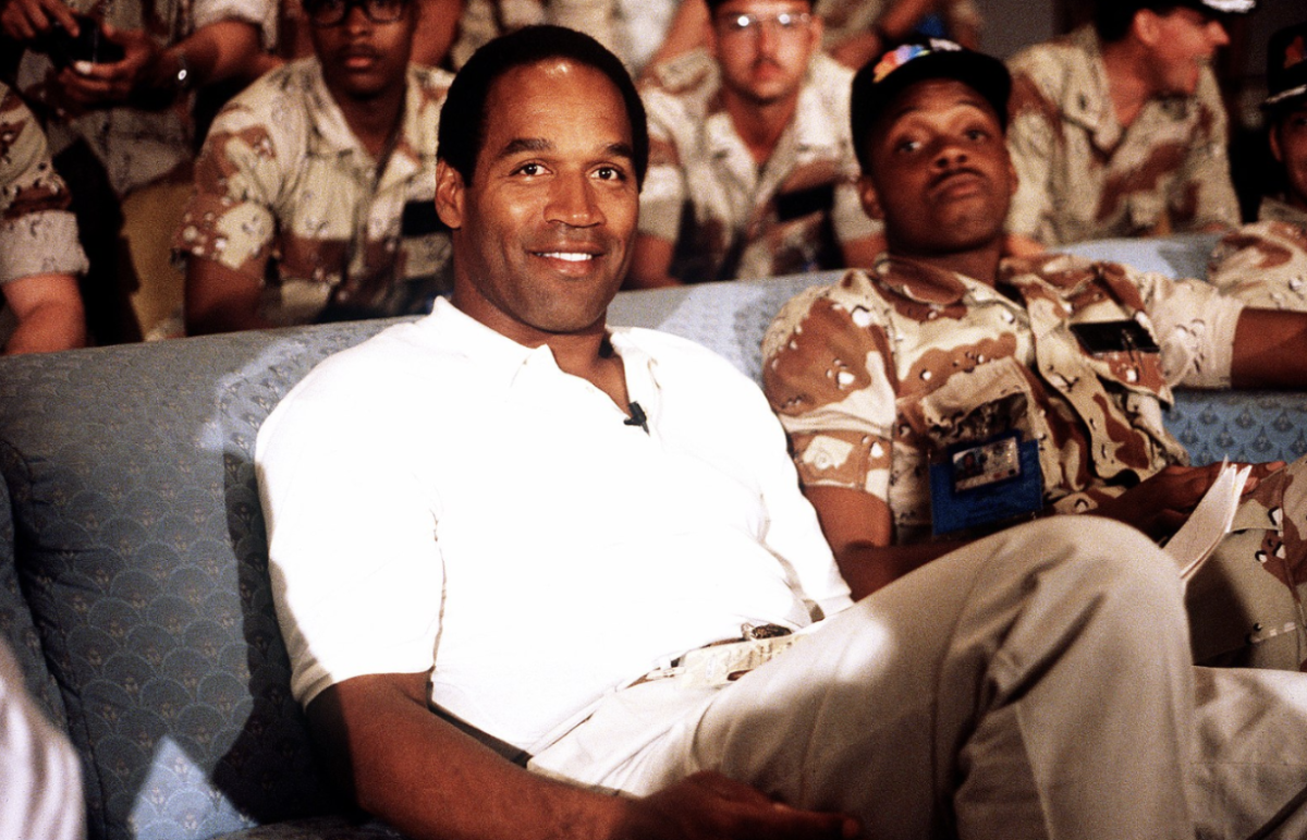 Simpson sits with a group of servicemen to watch a Thanksgiving football game in 1990. He was a professional football player, actor, and sports commentator.

