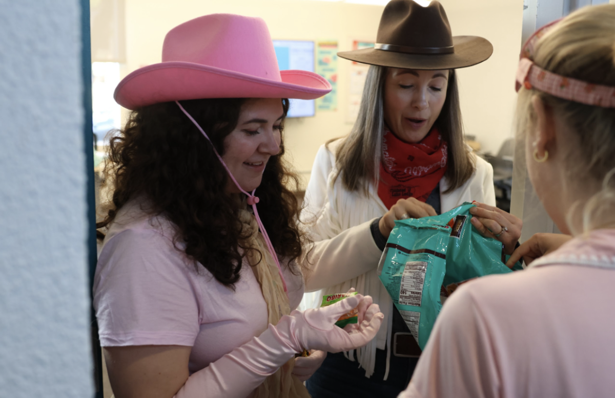 Faculty Lindsay MacGarva and Heather Wells pass out candy to students. In addition, students dressed up in costumes gather around the balcony on the Pine Octavia campus to watch Halloween dance performances on the first floor. 