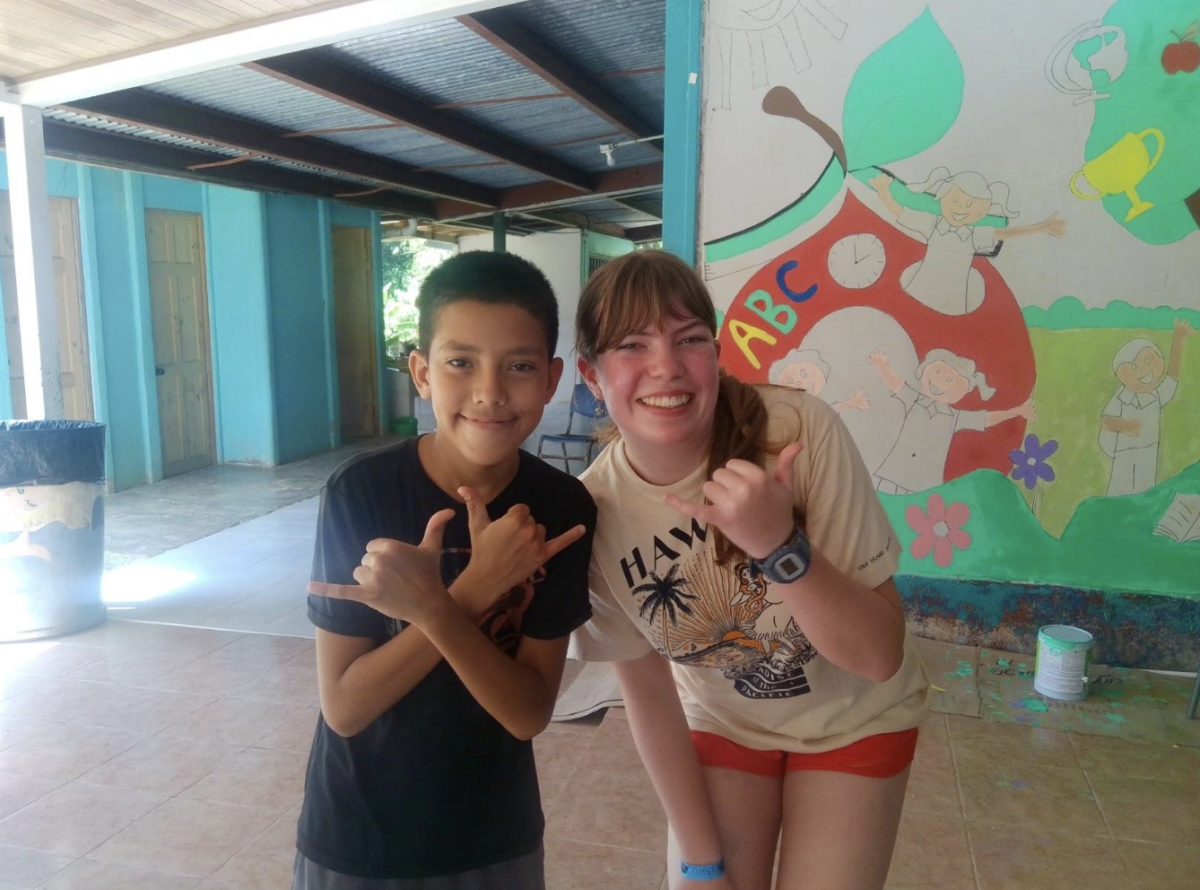 Eliza and Adrian take a photo at the school in front of the in-progress mural. They hold up the shaka hand symbol, which is closely associated with the Costa Rican phrase “Pura Vida”.
