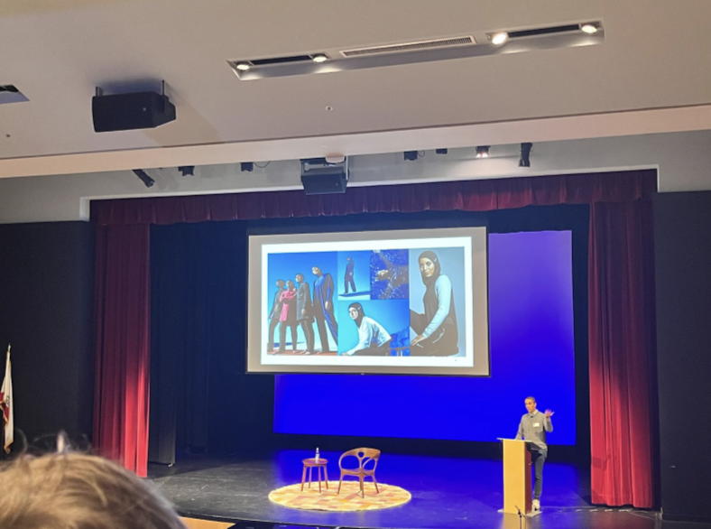 Cor Unum guest speaker Eboo Patel adresses high schoolers in Syufy theater. In this slide, he is discussing the importance of religious diversity and inclusivity, specifically regarding Nike’s release of modest swimwear. 