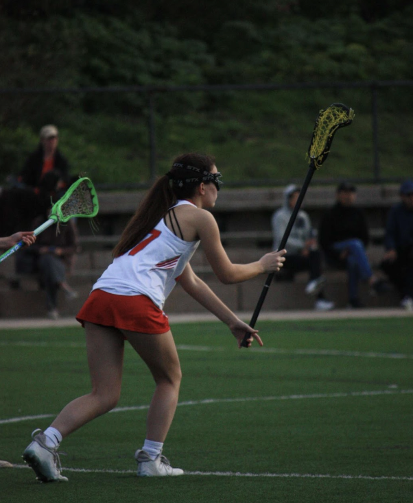 Freshman Claire Woodard approaches the opposing team with her stick raised high. Woodard scored later during the match, proving to be an asset on the Varsity team. 