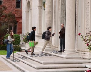 Students walk into the Flood mansion building before school begins. Before the walk through the front doors, they greet Community Life Chair Paul Pryor Lorentz. 